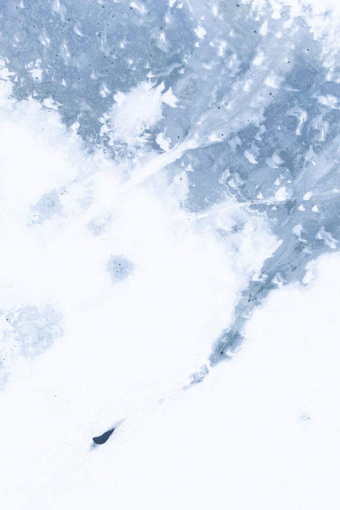 Frozen reservoir surface with soft blue ice textures and delicate snow patterns